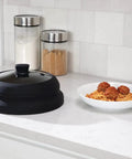 Mess Free Microwave Splatter Cover With Foldable Design for Quick Cleanup beside a plate of spaghetti on kitchen counter