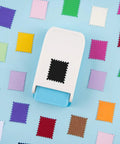 Rectangular Postage Stamp Punch 1x0.8 Inch With Scalloped Edge, Lever Action Paper Punch surrounded by colorful paper samples.