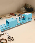 Mini Wood Lathe for Desktop Use with 7 Speed Settings 96W Motor Up to 9000 RPM on a workspace with tools for small wood projects.