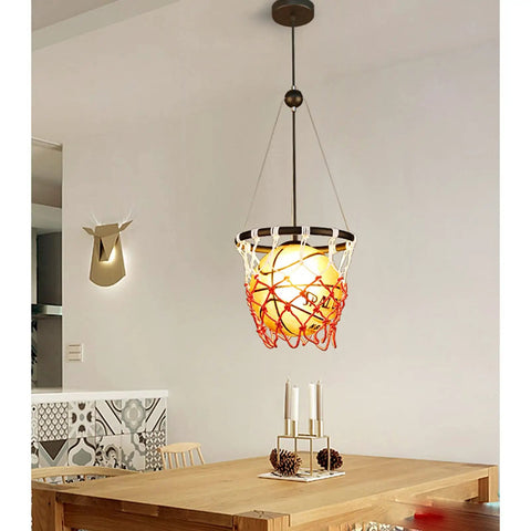 Basketball Hoop Pendant Light With Net and Acrylic Shade hanging over dining table, vintage style for kids' room, gym, or loft.