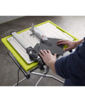 User operating the Badass 7 Inch Portable Wet Tile Saw With Tough Stainless Steel Table for precise ceramic cutting.