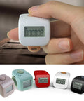 Slick Smooth Game Changer Digital Finger Counter For Rosary Prayer Beads Or Gym Reps With Six Channel Memory Backup and Quick Chargeable Silicone Wrist Strap held in hand.