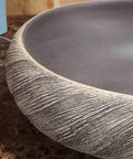 Close-up view of USZWBY Vessel Sinks Bathroom Vessel Sink Washbasin ceramic washbasin with textured edge on countertop.