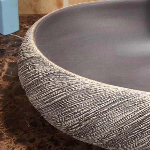 Close-up view of USZWBY Vessel Sinks Bathroom Vessel Sink Washbasin ceramic washbasin with textured edge on countertop.