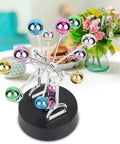 Colorful battery powered Newton pendulum ball desktop toy for science nerds on a black base, Newton's cradle style decor.