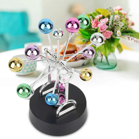 Colorful battery powered Newton pendulum ball desktop toy for science nerds on a black base, Newton's cradle style decor.