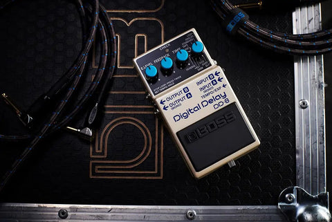 Digital Delay Guitar Effects Pedal With 11 Modes, resting on a black stage case, surrounded by coiled audio cables.