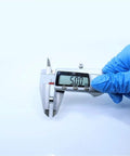 Digital caliper measuring 5.00 mm size in hand with a blue glove over a plain background for precise measurement of small objects.