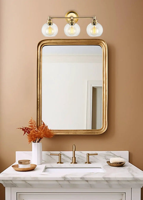 22 Inch Modern Three Light Vanity Bathroom Light With Clear Glass Globe Shades And Warm Brass Finish Above Sink