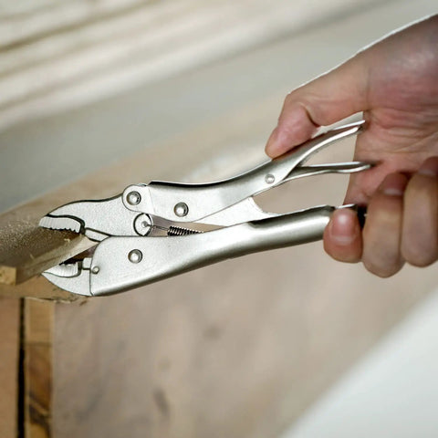 Hand using 7 Inch Curved Jaw Locking Pliers With Wire Cutter And Adjustable Wrench to grip a wooden plank
