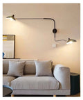 Slick Adjustable Double Head Wall Sconce Lamp In Modern Black Finish With Swivel Pole Design For Cozy Bedroom Reading Vibes And Chic Home Decor Upgrades mounted by a gray sofa.