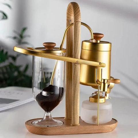Top Shelf Belgian Siphon Coffee Maker With Stunning Gold Finish Built From Heavy Glass And Steel Frame Relies On Steam Heat And Gravity Action To Pull Silky Smooth Brews Fast Sick Flex For True Coffee Geeks Wanting Elite Taste At Home Or Work with borosilicate glass and wooden base.