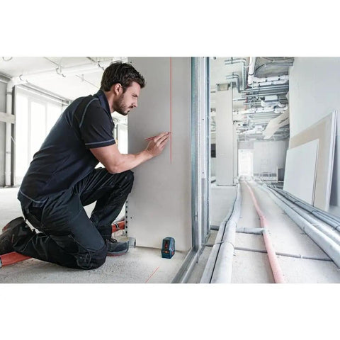 Person using GLL50-RT Self-Leveling Cross Line Laser Renewed for accurate layout in construction, bright red beam visible.