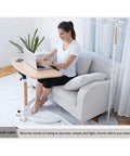 Mobile Height Adjustable Standing Desk With Sturdy Silent Rolling Casters And Flexible Tray Surface Perfect Over Bed Support For Bed Rest Or Kickback Home Office Lounge, used by a woman on a sofa.