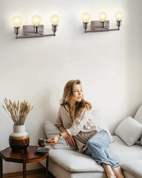 Woman in living room under Three Light Brushed Nickel Bath Vanity Fixture Up Down Wall Sconce Sleek Modern Industrial Retro Metal Wall Lamp
