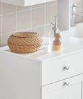White Slim Tilt-Out Laundry Hamper Cabinet For Tight Spaces with decorative items on top