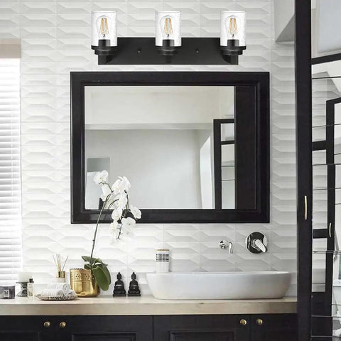 Three Light Matte Black Vanity Light With Seeded Glass Shades Above Bathroom Mirror