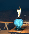 Blue glass torch on table, part of a Four Pack Glass Table Top Outdoor Torches With Citronella Refillable Glass Lanterns For Garden Patio.