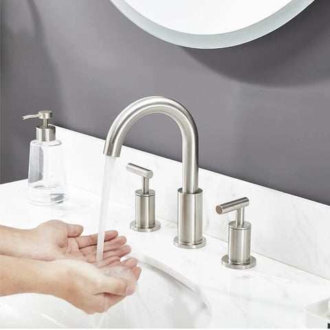 Bathroom sink with Three Hole Widespread Brushed Nickel Bathroom Faucet with two handles, water flowing, pop up drain visible