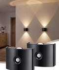 DEXULESA 2 Pack Motion Sensor Wall Light Magnetic Rechargeable Wall Sconce in black mounted on a wall, casting warm light.