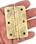Set Of 4 Embossed Brass Hinges With Floral Pattern For Wooden Chest Trunk Cabinet Cupboard Doors, shown in hand for scale.
