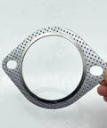Close-up of a 3 inch exhaust gasket with perforated metal flange and two bolt holes for 3 inch muffler flange manifold