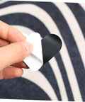 Hand holding a piece of Heart Shaped Rug Tape Set 8 Pcs No Fuss Non Slip Double Sided Stickers For Area Rugs And Carpets Easy Install No Residue