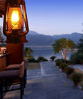 Pack Of 2 Vintage Rustic Lantern Lamps With Edison LED Bulbs, Bronze Rust Finish, hanging in outdoor setting near bar area.
