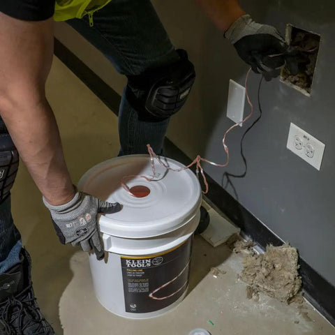 Person pulling Poly Pull Line For Wire Pulling, Orange Tracer Cord, Light Duty Cable String, 6500 Foot Length, from a wall outlet