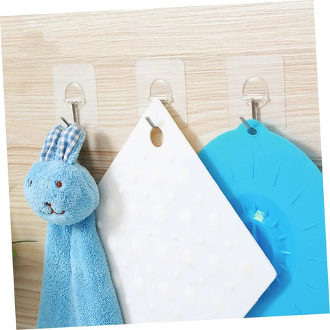 Super Tough Clear Adhesive Wall Hooks 12 Pack Stainless Steel holding a blue bunny plush and hanging items on a wood surface.