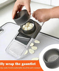 Front view of gray mandoline slicer with safety hand guard, 6-in-1 design; garlic cloves shown.