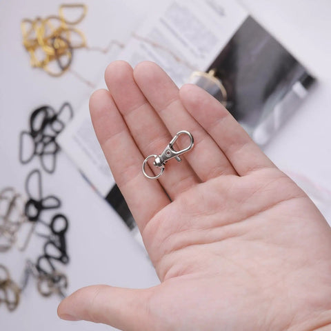 Hella Durable Premium Silver Swivel Snap Hooks 50 Pack Lobster Claw Trigger Clasps shown in hand for keychains and lanyards.
