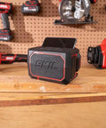 Heavy Duty Portable Bluetooth Speaker With Kickass Bass And Wireless Audio on a workbench with a phone dock.