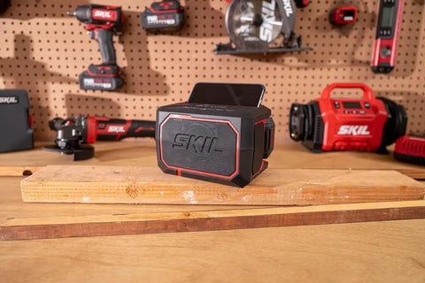 Heavy Duty Portable Bluetooth Speaker With Kickass Bass And Wireless Audio on a workbench with a phone dock.