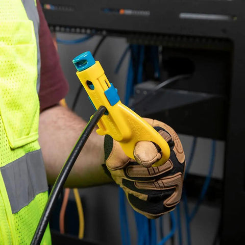 Person using Data And Coax Cable Stripping Tool With Radial Design For RG59 RG6 And CAT3 To CAT6A on black cable wearing gloves.