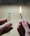 Relightable Bullet Fire Starter Keychain Lighter For Camping And Grilling in use, flame ignited, metal bullet design shown in hand