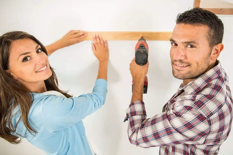 Man and woman measuring and drilling in home renovation project