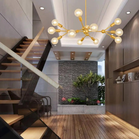 Modern Sputnik Chandelier 12 Light Gold Metal Ceiling Fixture for Living Room Bedroom Dining Kitchen and Office Dope Statement Lighting with E26 Base LED Compatible Bulbs Not Included 38.6 Inch Diameter hanging in a modern interior with wooden staircase and plant.