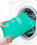 Two Pack Large Travel Laundry Bags Waterproof Wet And Dry With Drawstring Closure, Green bag being placed into washing machine