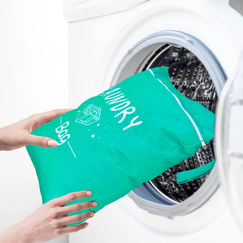 Two Pack Large Travel Laundry Bags Waterproof Wet And Dry With Drawstring Closure, Green bag being placed into washing machine