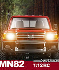 Front view of RC Beast Rock Crawler Truck 4x4 Toyota LC79 One Twelfth Scale Off Road Pickup with headlights on in forest setting.