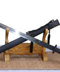 Beefy Damascus Tang Dao Sword With Black Gold Finish displayed on a wooden stand, showcasing full tang build and intricate details.