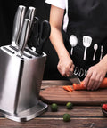 Six Slot Stainless Steel Knife Holder Rack With Anti Skid Pad next to person cutting carrot on wooden board