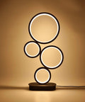 4 Circle Dimmable LED Table Lamp with Color Adjustable Light, Slick Modern Round Design, 12W, Black Finish, glowing on shelf