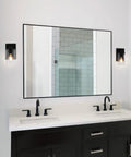 Farmhouse 4 Light Matte Black Bathroom Vanity Light With Clear Tubular Glass Shades Over Mirror Wall Fixture Dope Industrial Vibe Hardwired Up Or Down Mount For Bath And Bedroom shown beside a large vanity mirror and sink.
