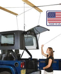 Overhead Truck Cap Garage Hoist With Self-Leveling Lift Safe Anti-Drop System One-Person Operation 12-Foot Ceiling Ready 200 Lb Capacity Four-Point Kit Made In USA Easy Install shows a woman operating the hoist.