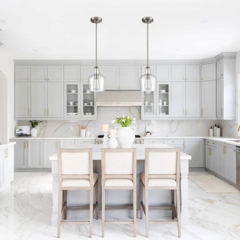 Modern Farmhouse Glass Pendant Light For Kitchen Island In Brushed Nickel Hand Blown Teardrop Shade 1 Light ETL Listed Wrought Iron Fixture Sloped Ceiling Adapter over a white kitchen island with gray cabinetry.