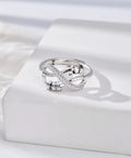 Silver fidget ring with knot design and spinning beads, showcased on a white surface for stress relief and focus.