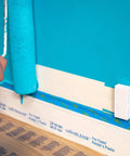 Person painting wall above concealed ultra flat adhesive speaker wire installation.
