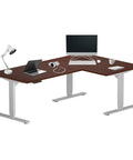 Huge Electric Height Adjustable L Shaped Corner Desk With A Massive 72X48 Inch Surface And Super Smooth Lift Mechanism For Your Next Level Home Office Build In Gray Frame And Dark Cherry Top, styled with laptop and lamp.